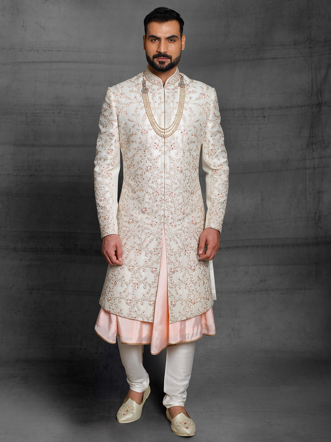 Cream sherwani with maroon highlights.