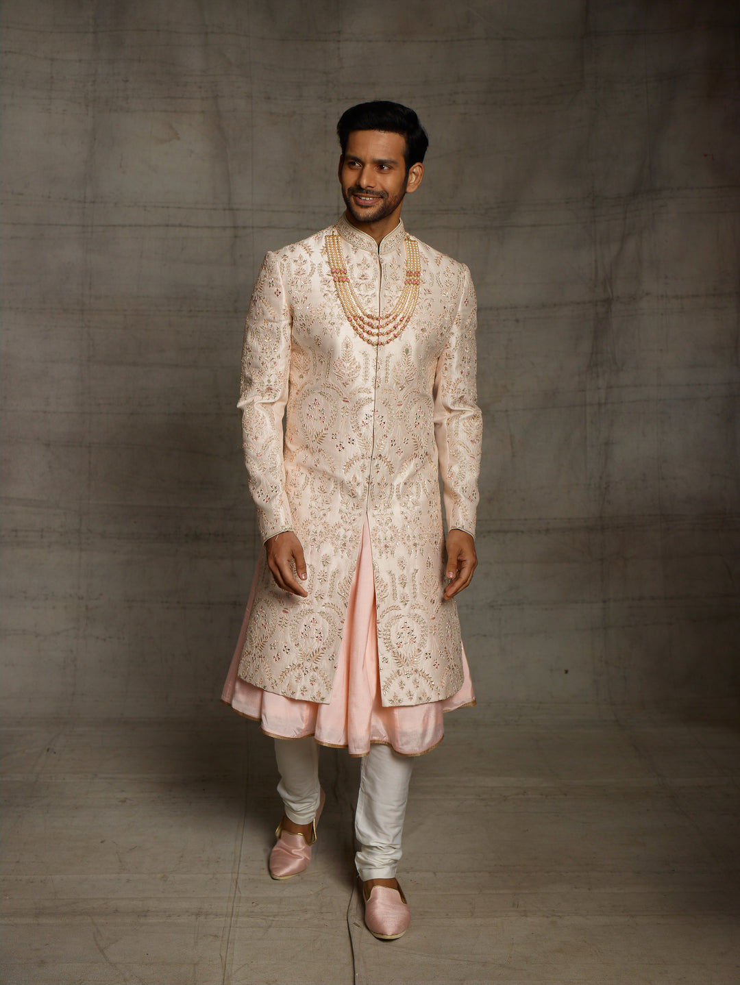 Powder peach sherwani with resham work and mirror highlights.