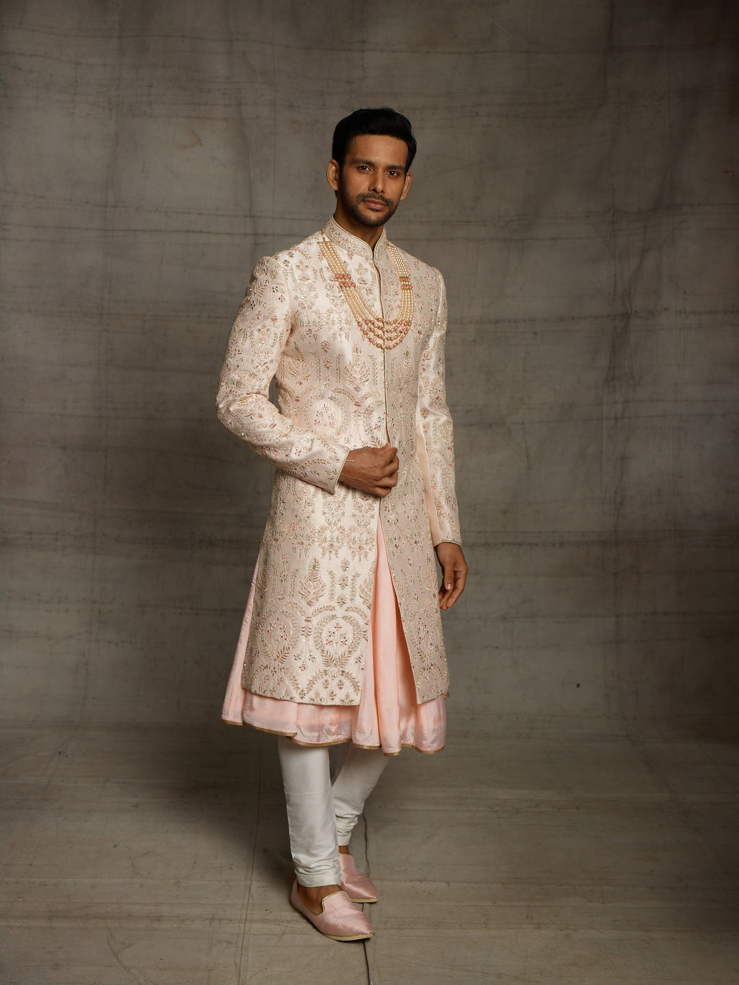 Powder peach sherwani with resham work and mirror highlights.