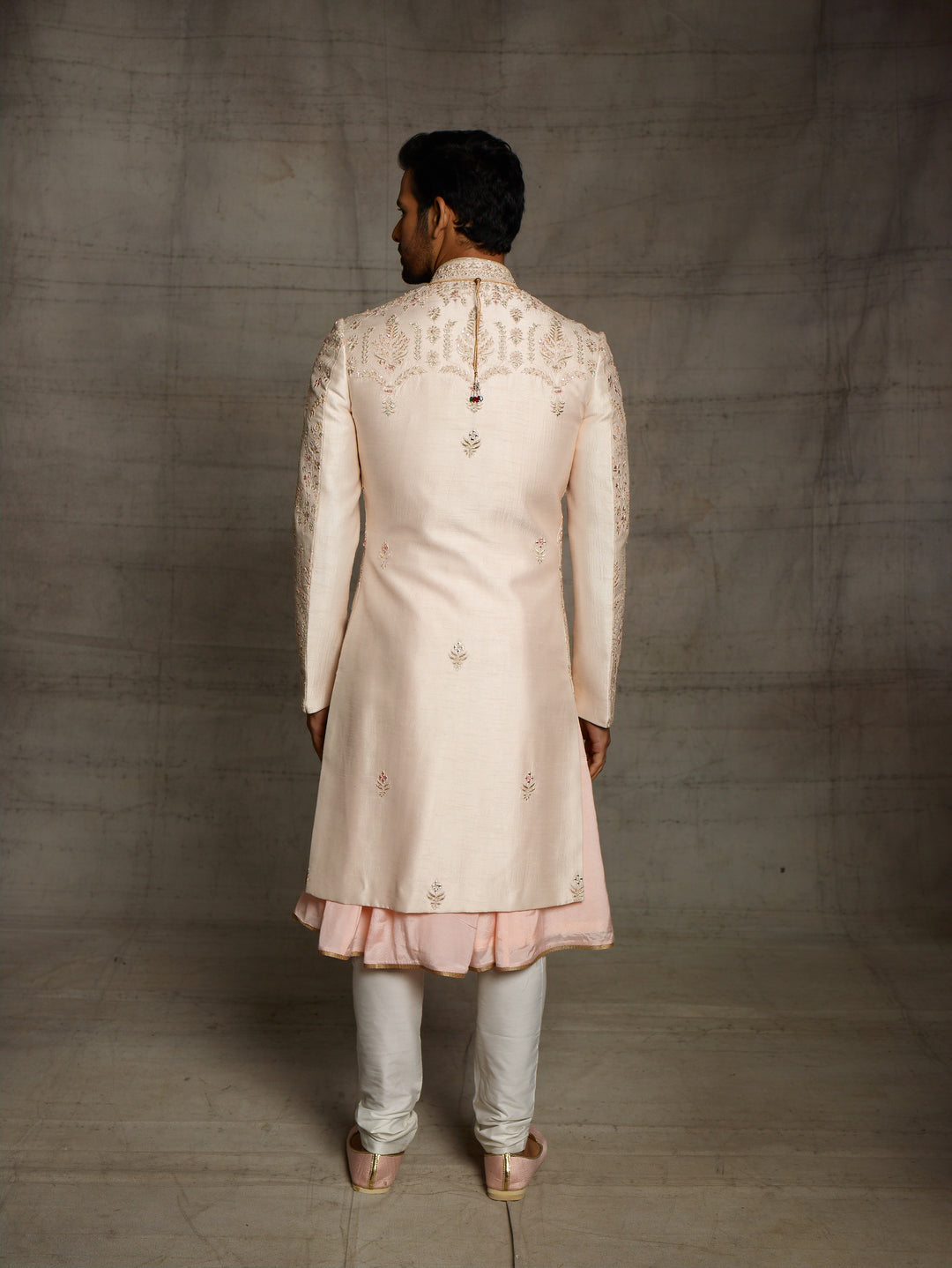 Powder peach sherwani with resham work and mirror highlights.