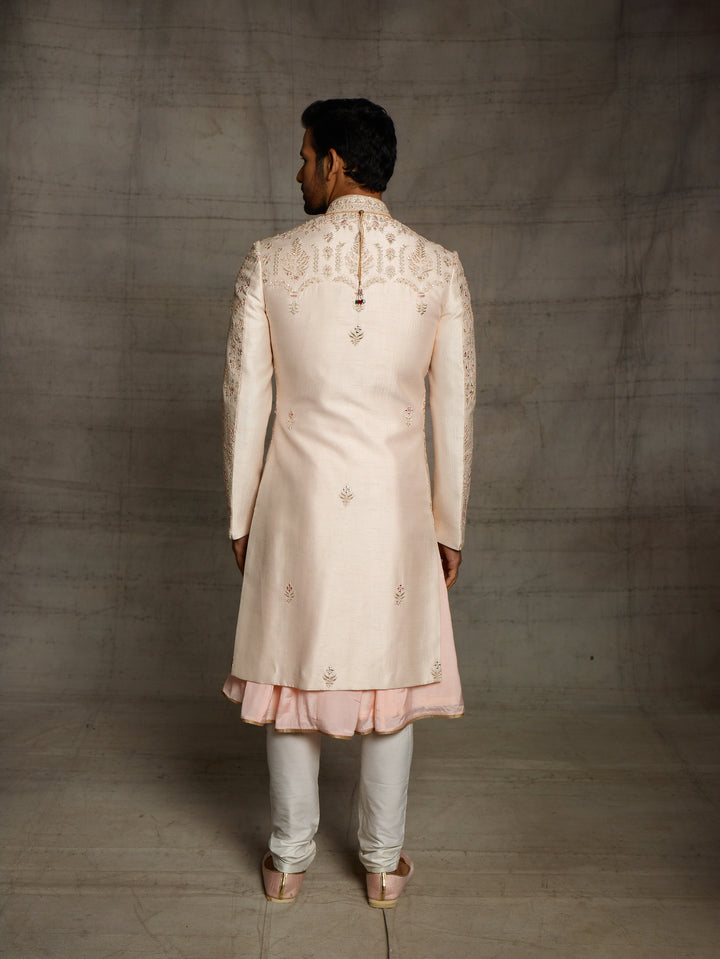 Powder peach sherwani with resham work and mirror highlights.
