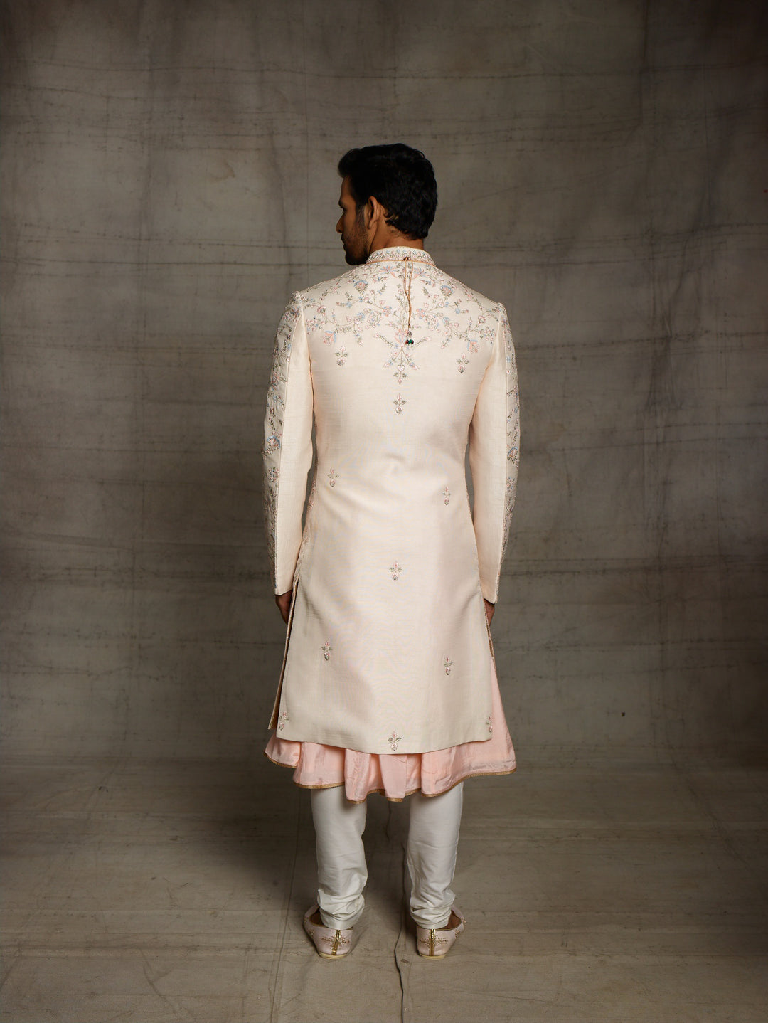 Peach groomswear sherwani with minimal blue highlights.