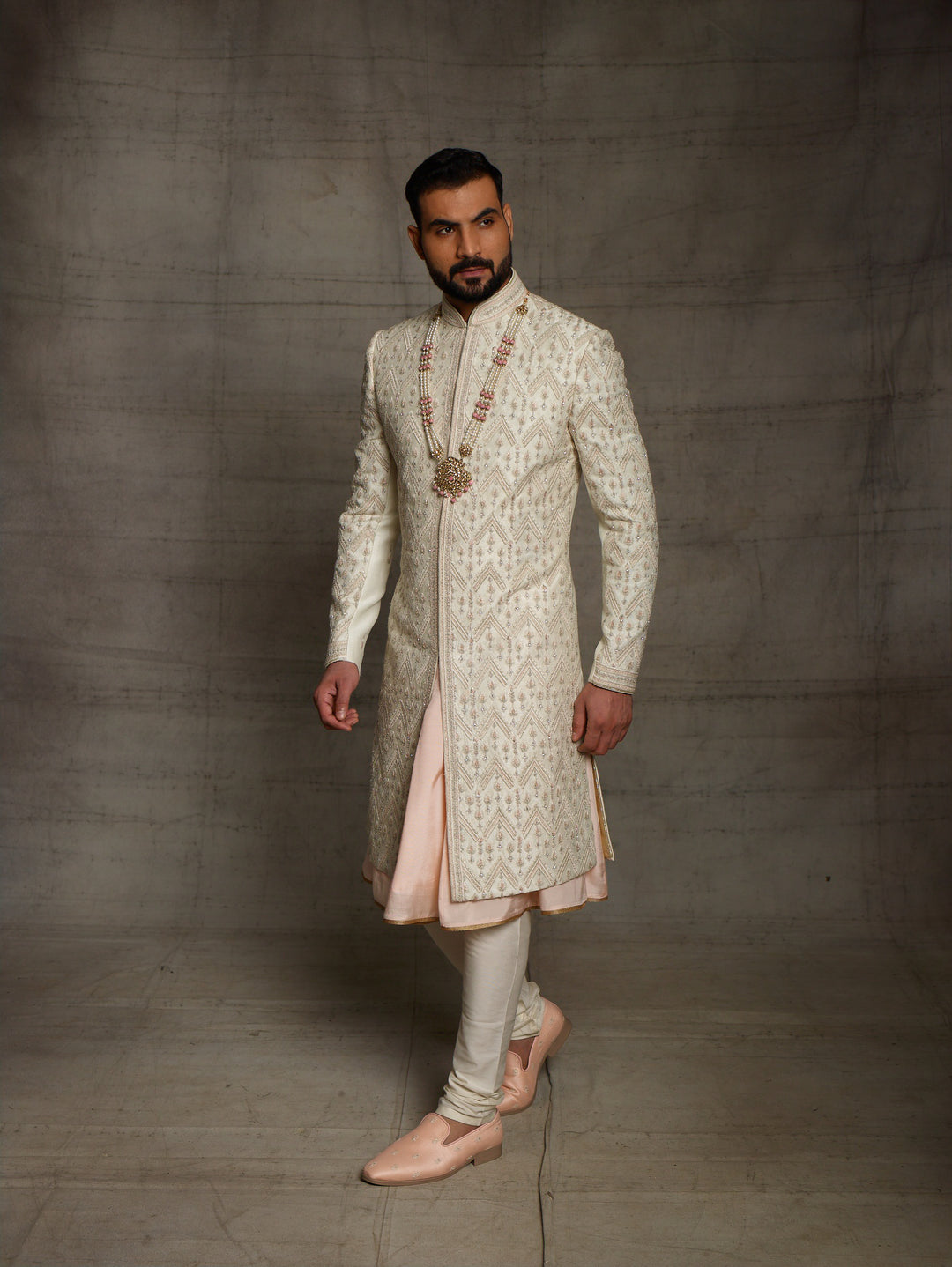Ivory sherwani with geometric work placement.