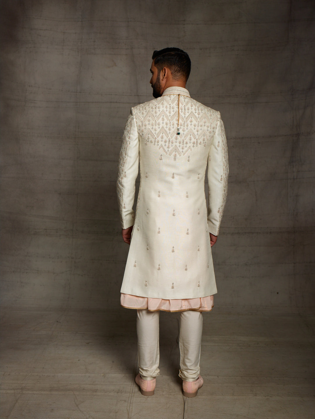 Ivory sherwani with geometric work placement.