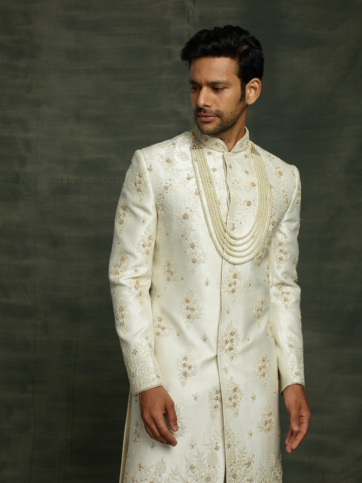 Off-white silk sherwani with floral work placement.
