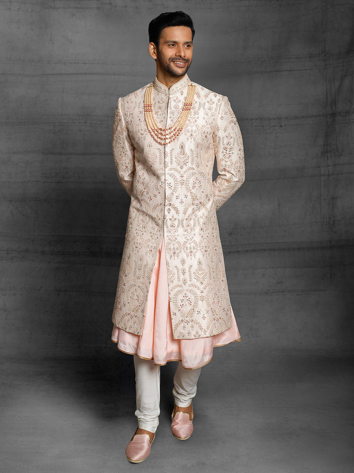 Powder peach sherwani with resham work and mirror highlights.