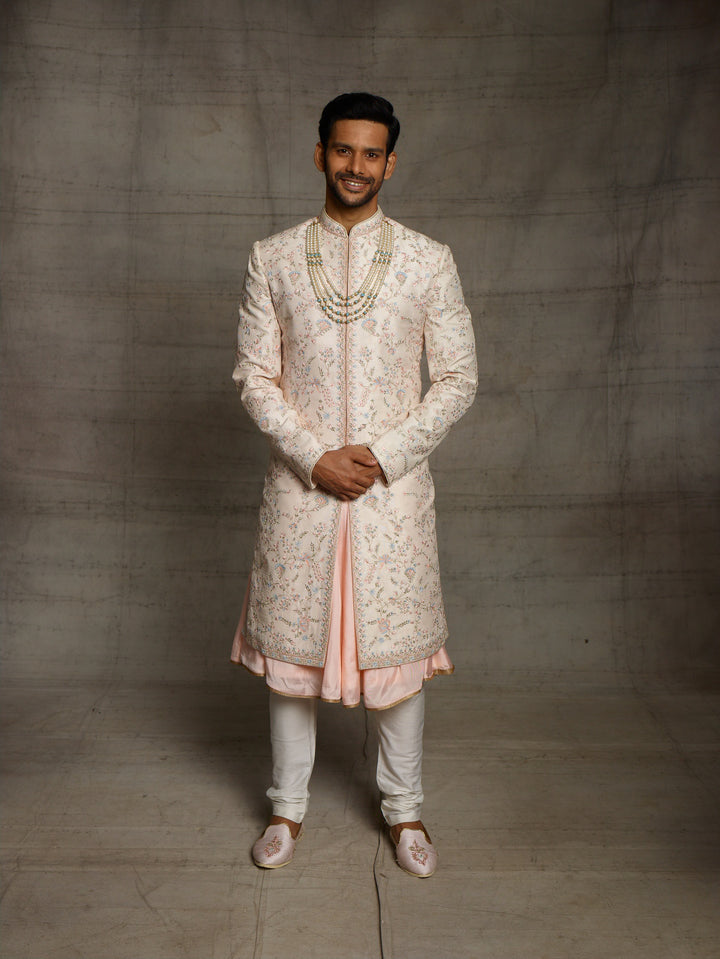 Peach groomswear sherwani with minimal blue highlights.